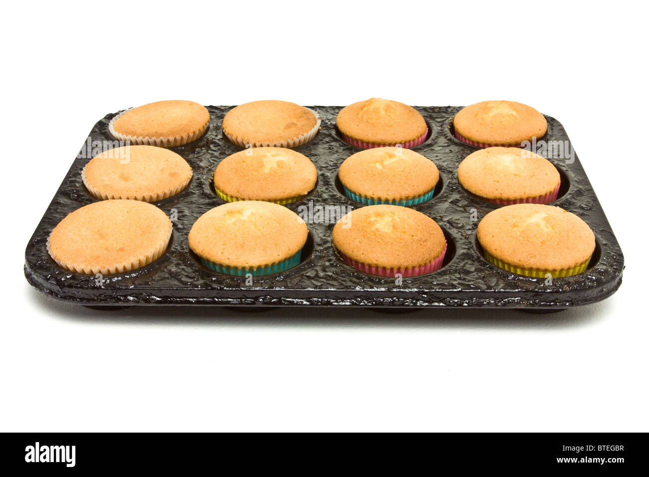 Freshly baked cup cakes still in baking tray straight from the oven on white. Stock Photo