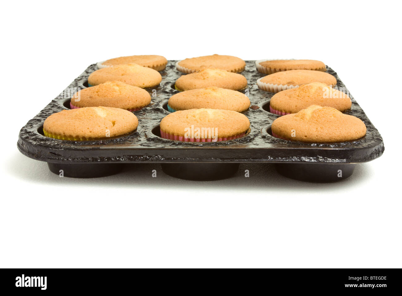 Freshly baked cup cakes still in baking tray straight from the oven on white. Stock Photo