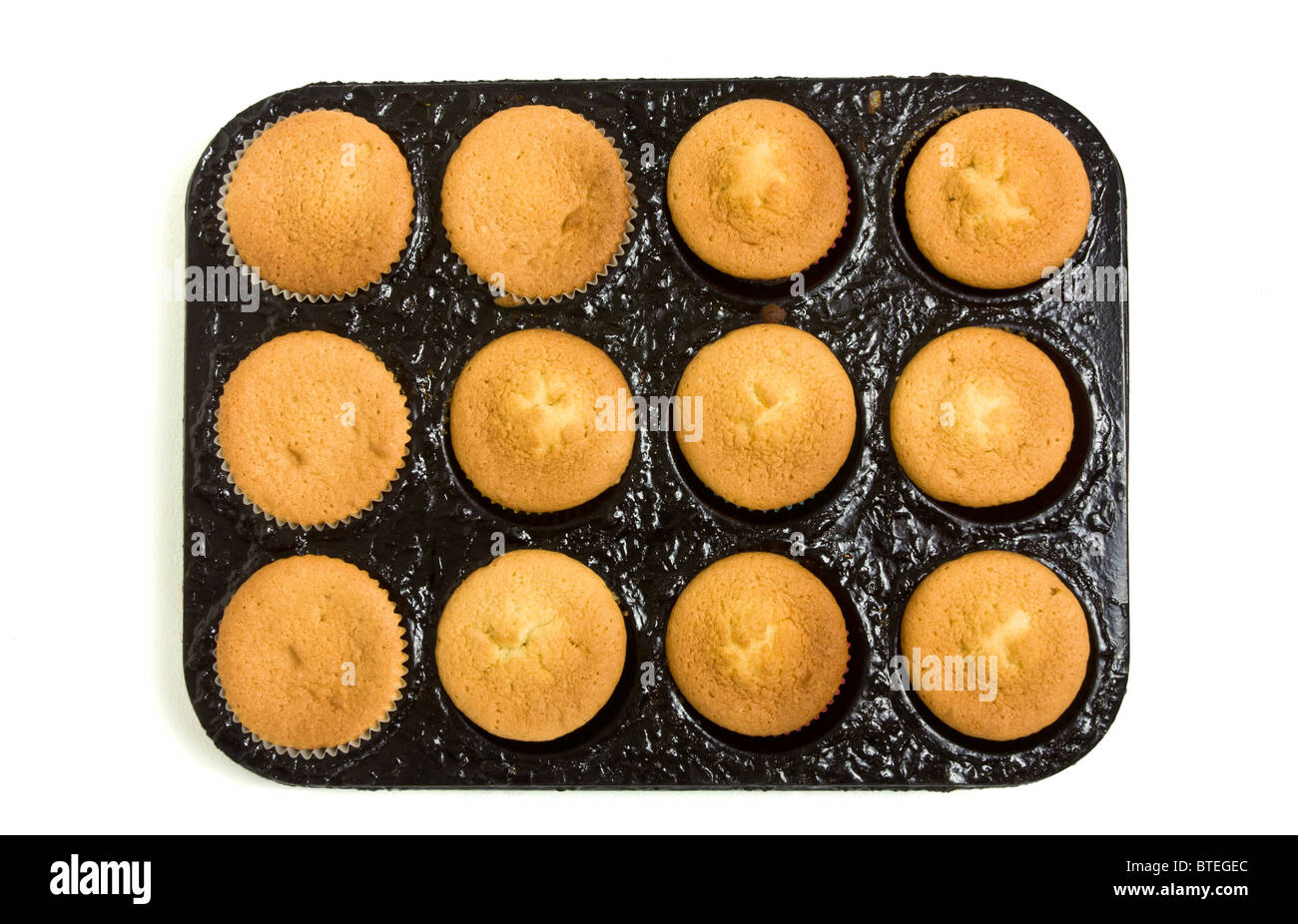 Freshly cooked cup cakes still in baking tray straight from the oven on white. Stock Photo