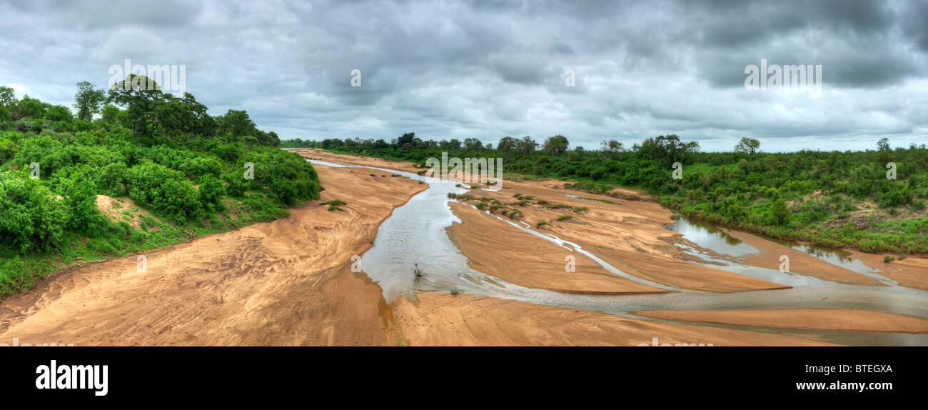 Shingwedzi river bed and some water flowing with thick vegetation on the riverbanks Stock Photo