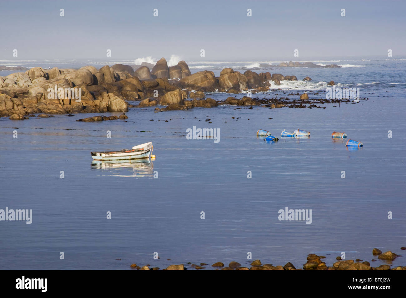 Crayfish traps and a wooden boat on the water at Jacobsbaai Stock Photo