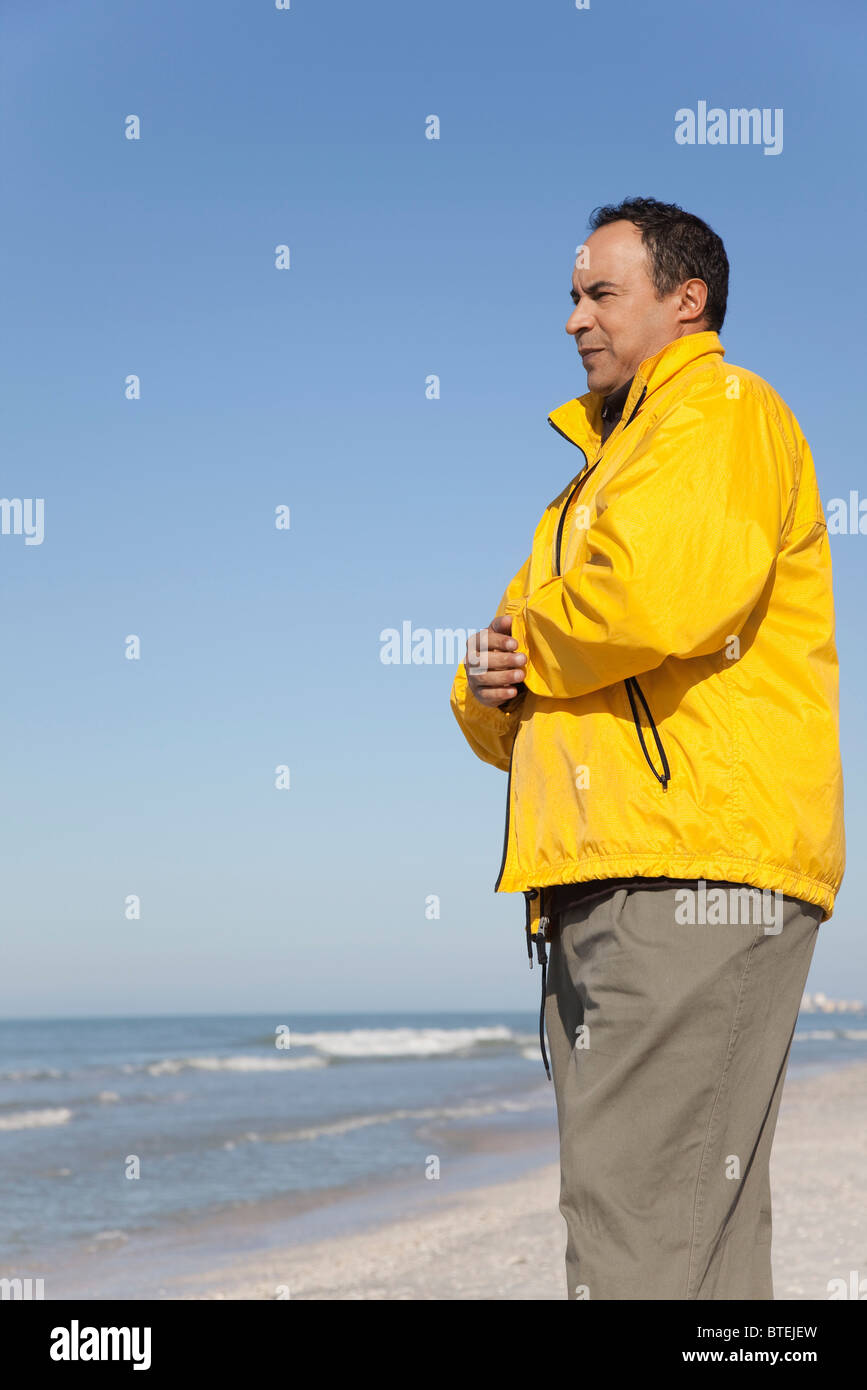 Mature man standing on beach looking at ocean Stock Photo - Alamy