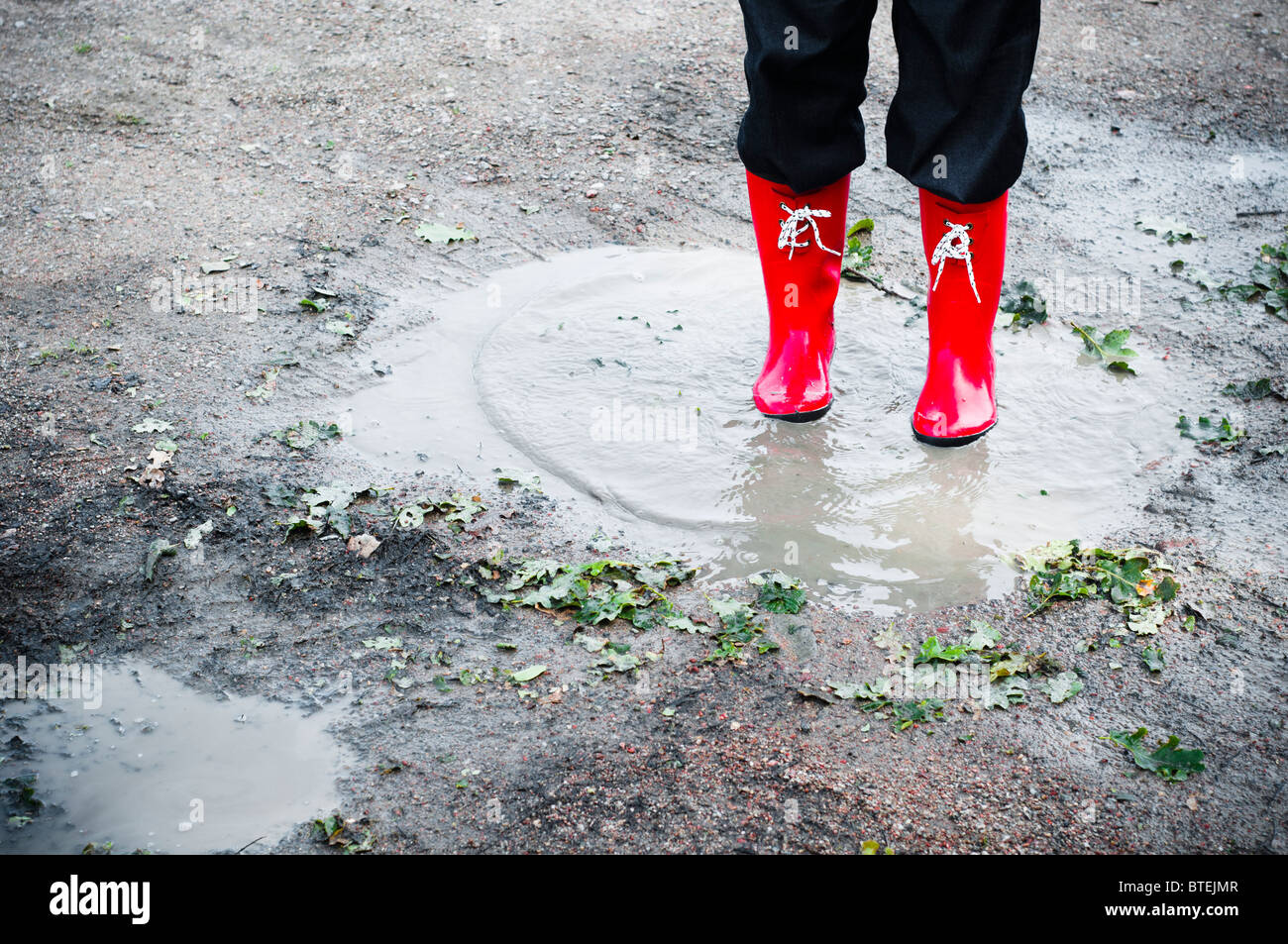 Woman in red wellingtons standing in a puddle Stock Photo - Alamy