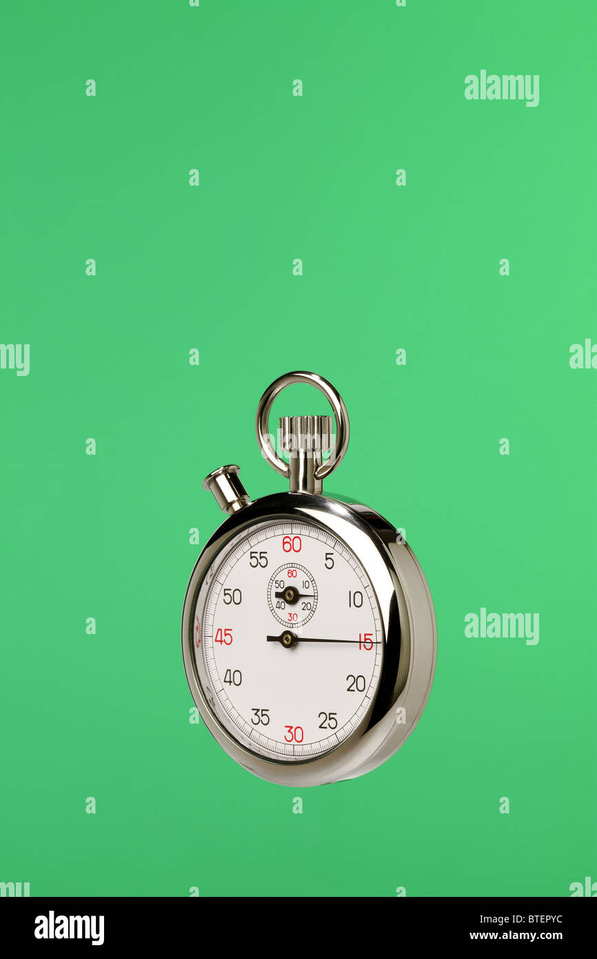 A stopwatch timing device floating on a green background Stock Photo