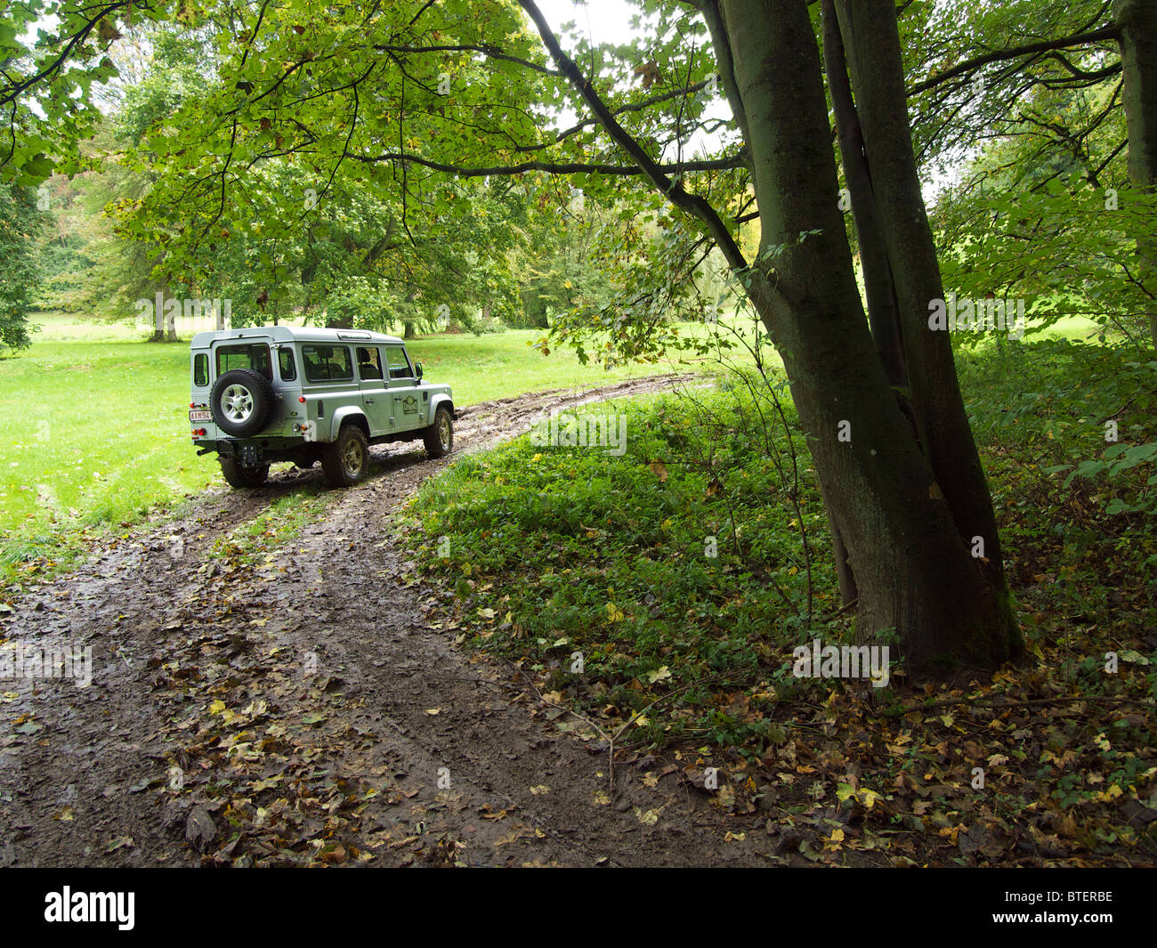 Silver Land Rover Defender standing still in a bend of a muddy path at Domaine d'Arthey estate, belgium Stock Photo