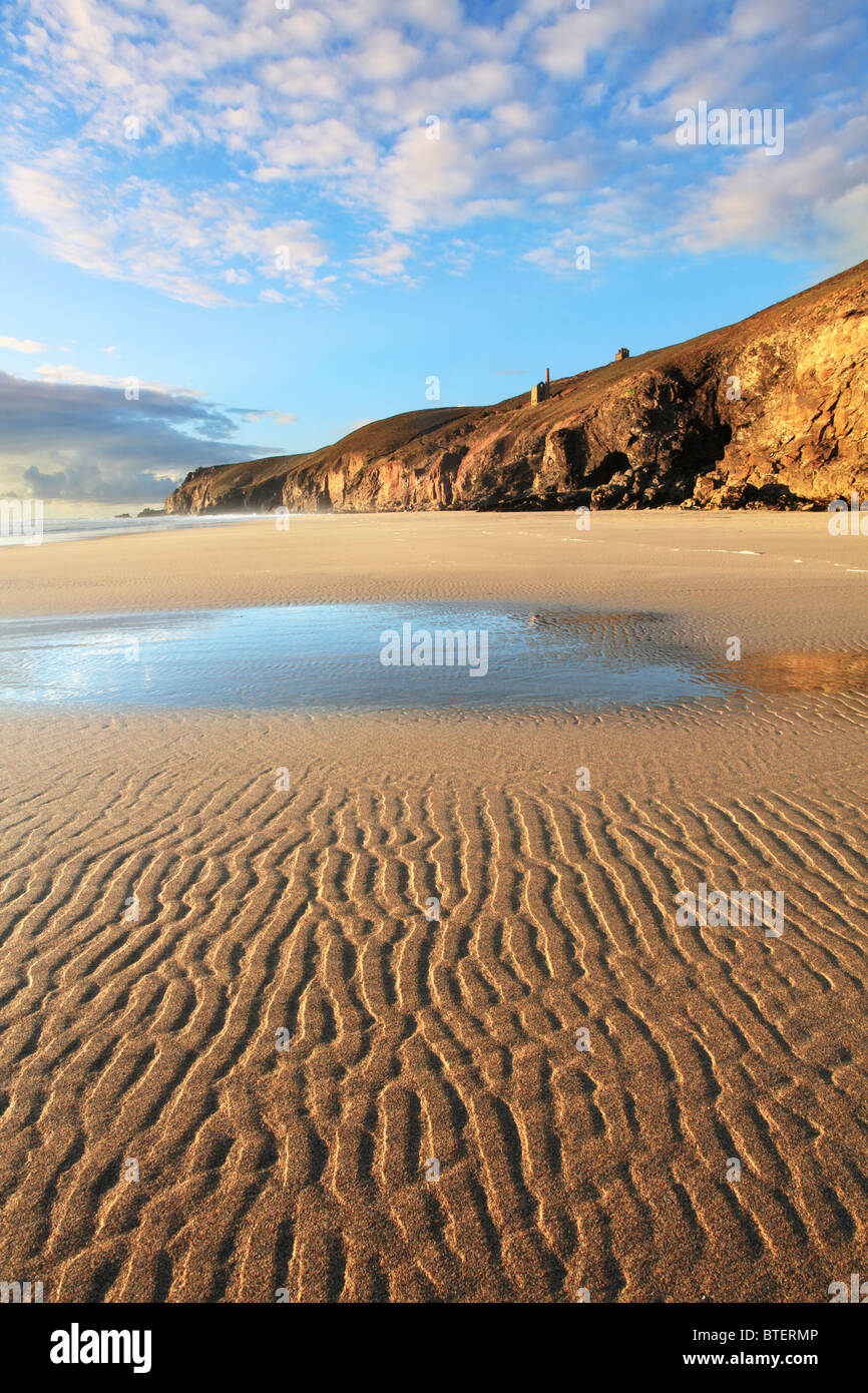 Chapel Porth beach on the north coast of Cornwall captured at low tide with St Agnes Head and Wheal Coates in the distance Stock Photo