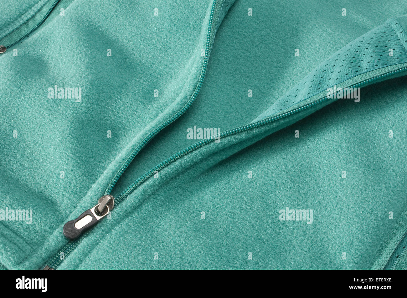 Close-up view of a green pastel colored jacket and the zipper section opening Stock Photo