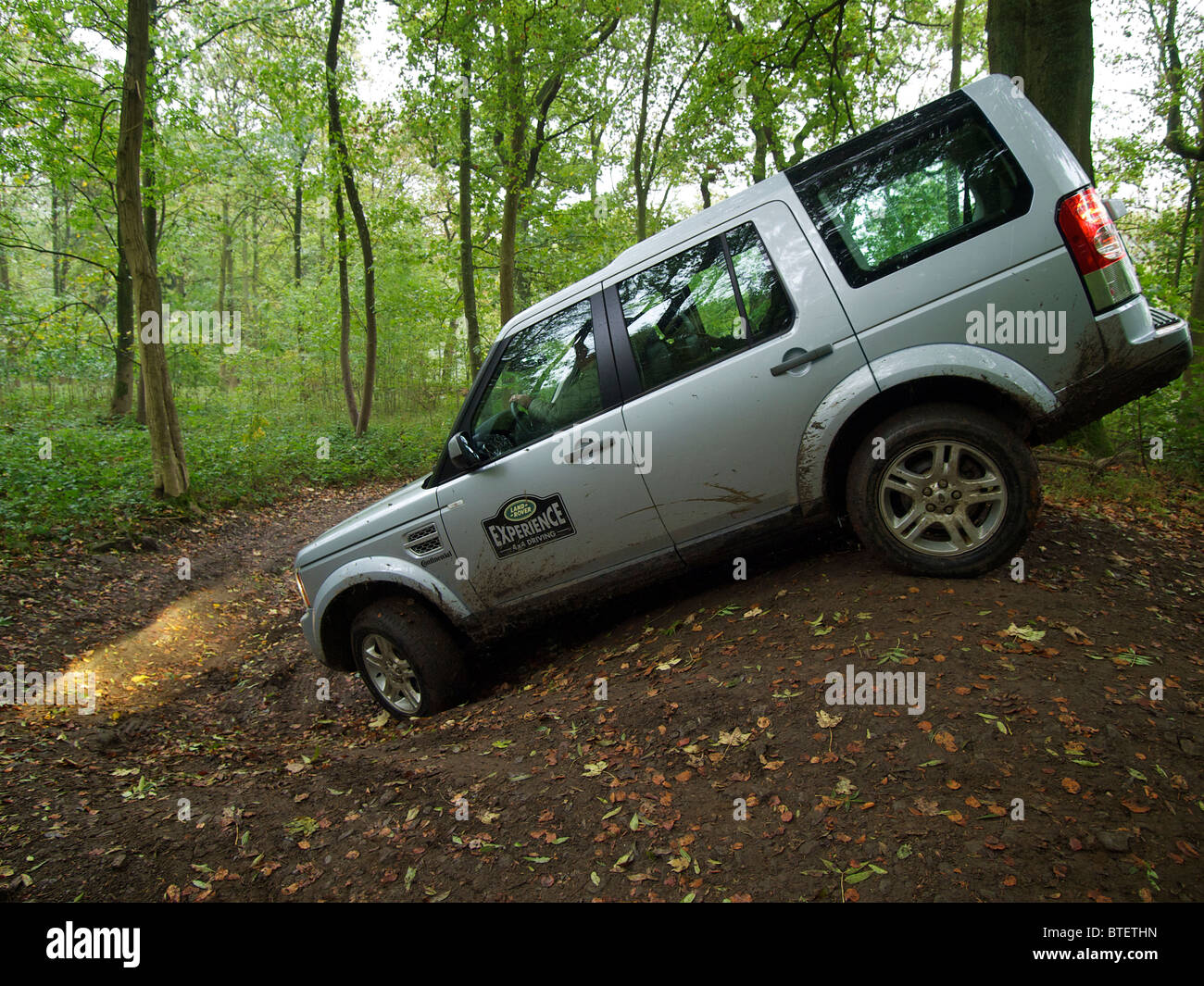 Silver Land Rover Discovery 4 driving through a forest at the Domaine d'Arthey estate in Belgium Stock Photo