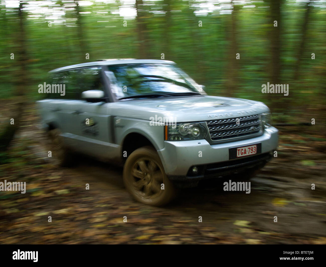 Range Rover driving along a very muddy path in the forest at Domaine d'Arthey estate, Belgium. with motion blur Stock Photo