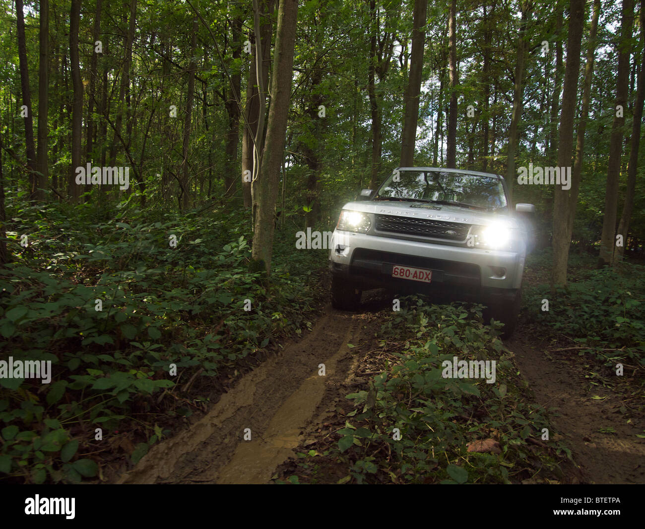 Range Rover Sport driving along a very muddy path in the forest at Domaine d'Arthey estate, Belgium Stock Photo