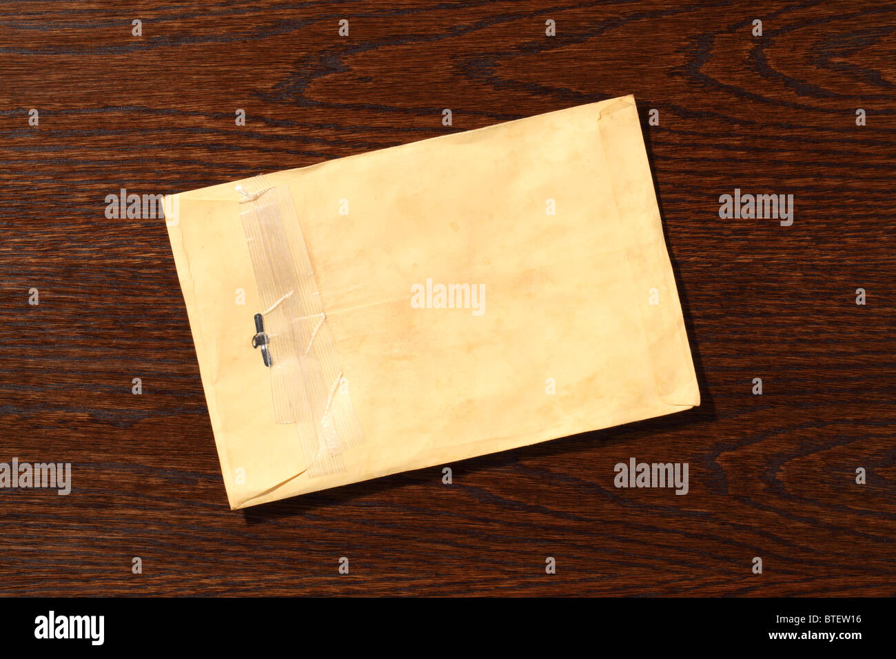A used postal mailing envelope torn open. A dark brown wood desk background Stock Photo Alamy