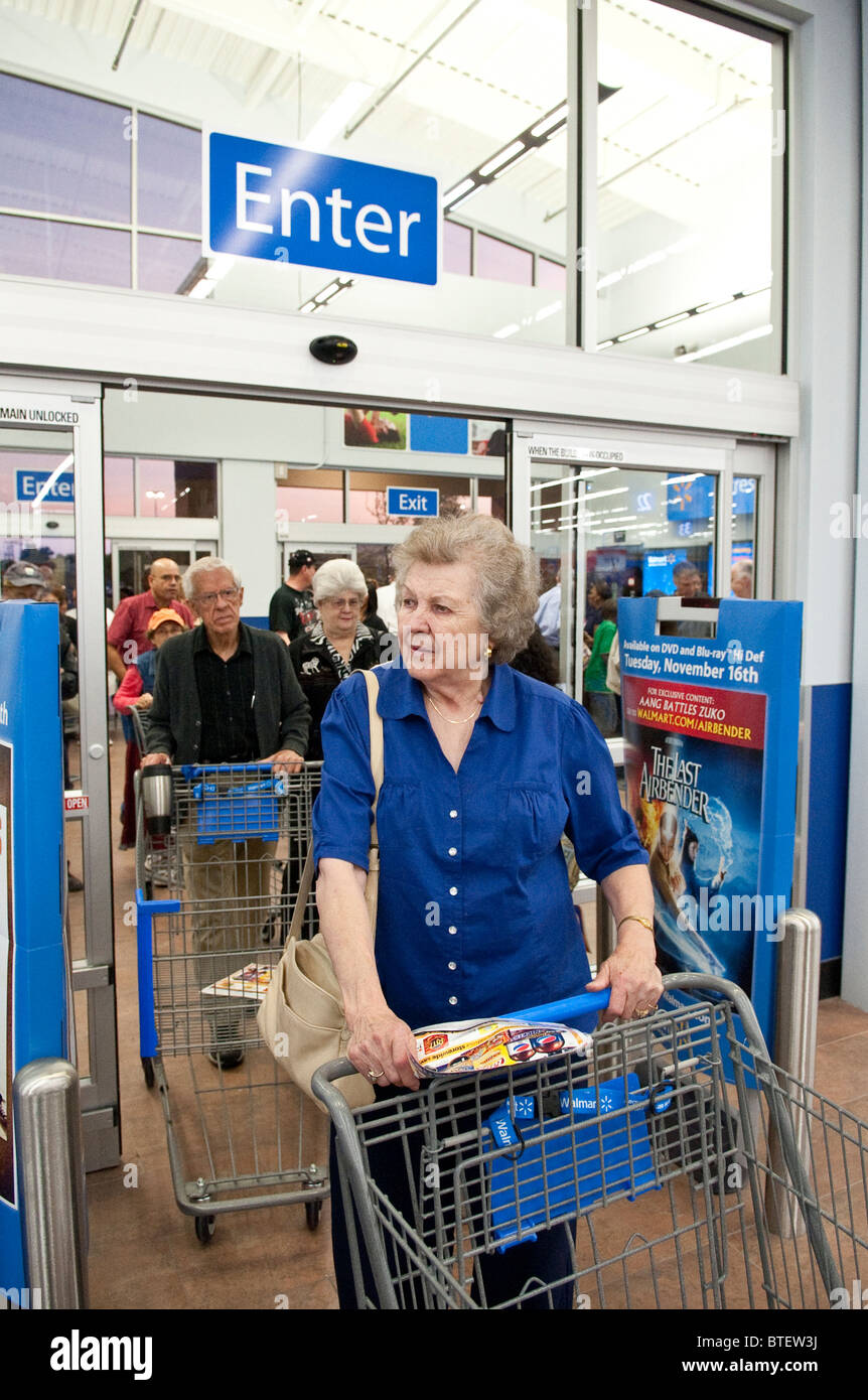 Male and female seniors push empty shopping carts through entrance of