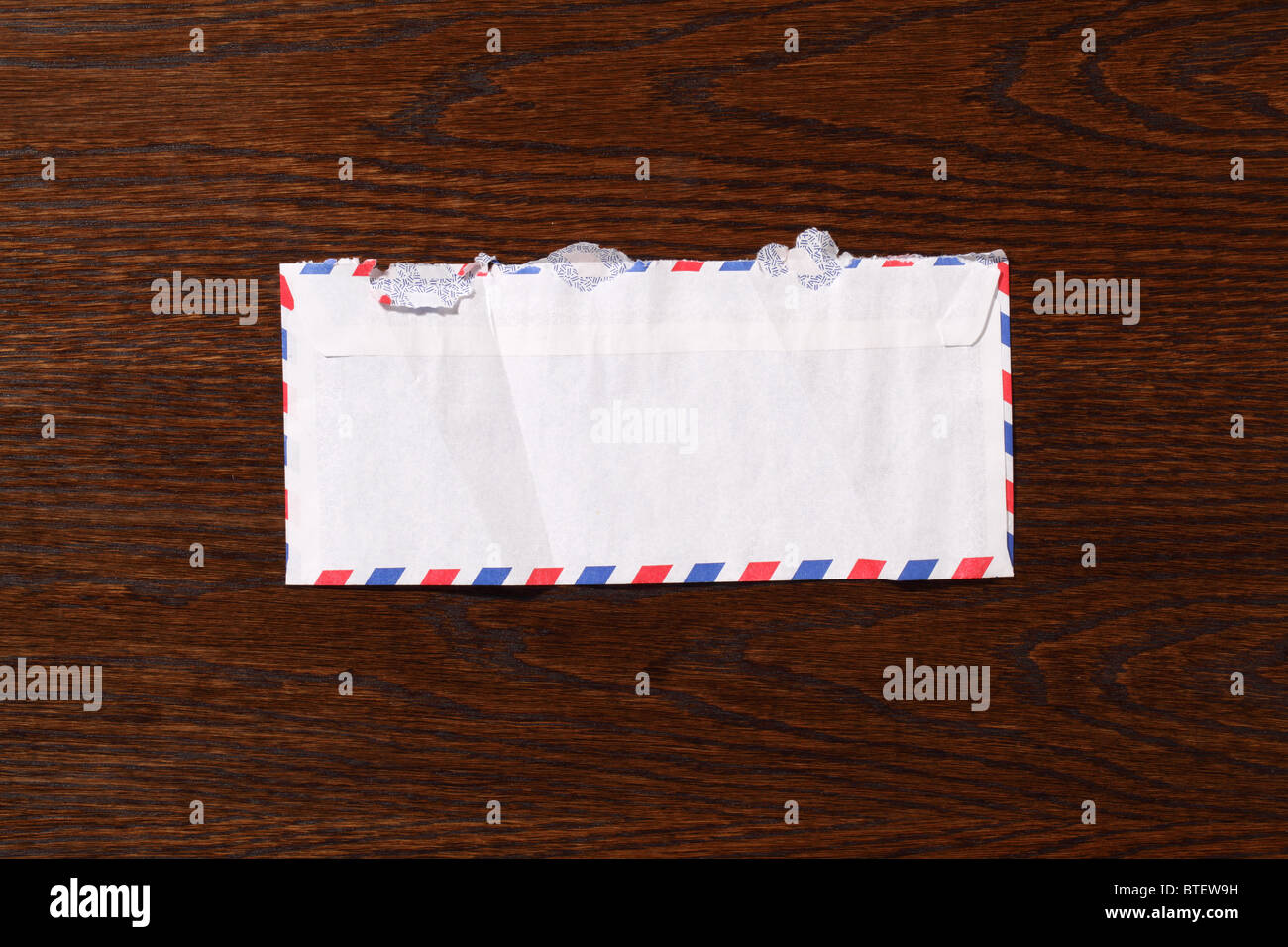A used postal mailing envelope torn open. A dark brown wood desk background Stock Photo Alamy