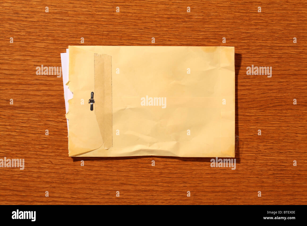 A used postal mailing envelope torn open. Brown wood grained background Stock Photo Alamy