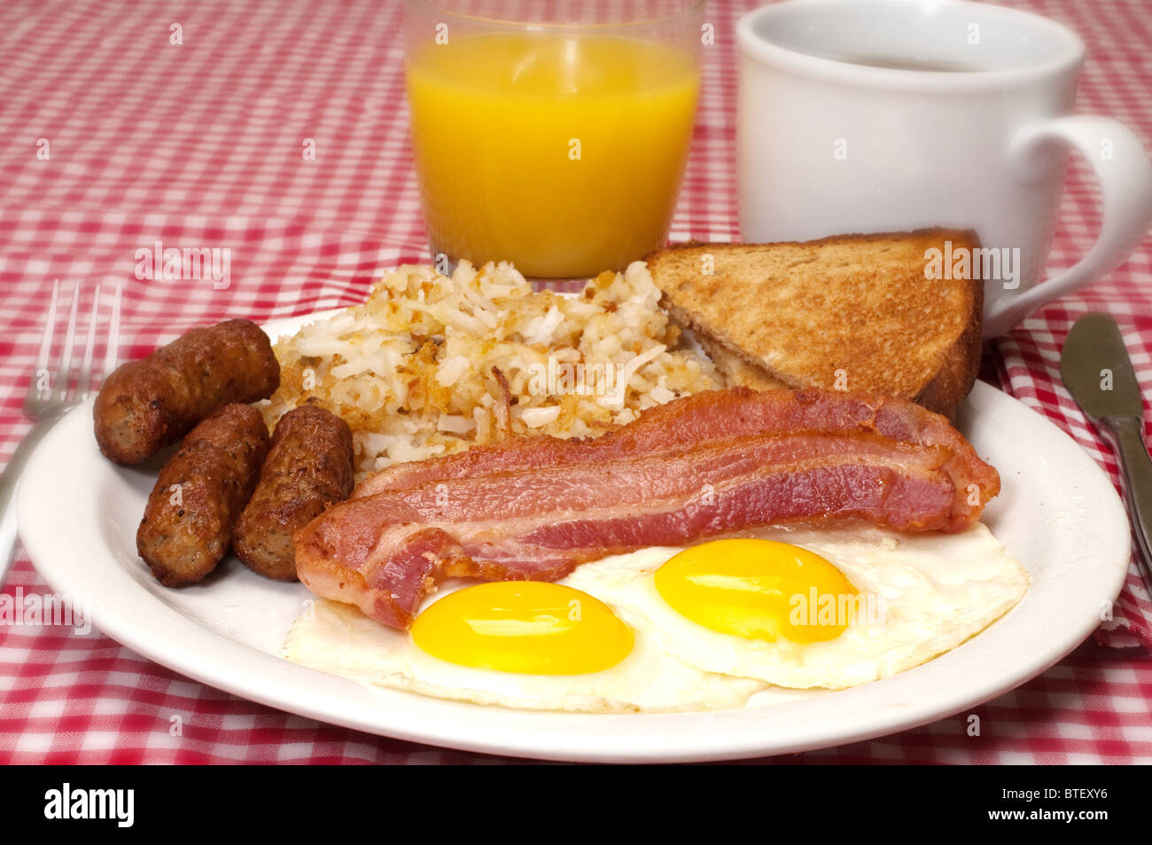 Breakfast plate with eggs sunny side up, bacon, link sausage, hash