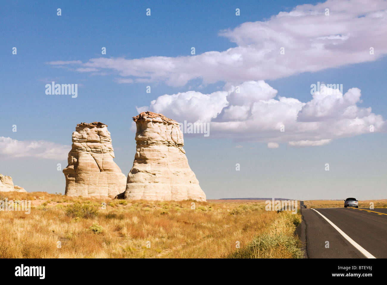 Sandstone sedimentary rock formations stand tall next to highway - Arizona USA Stock Photo