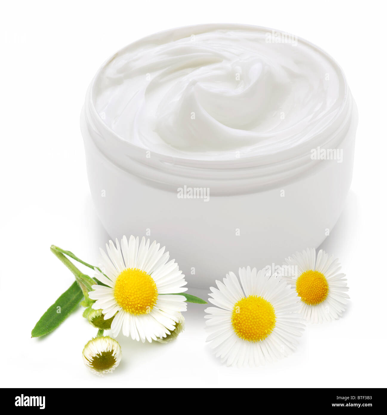 Opened plastic container with cream and camomile on a white background. Stock Photo