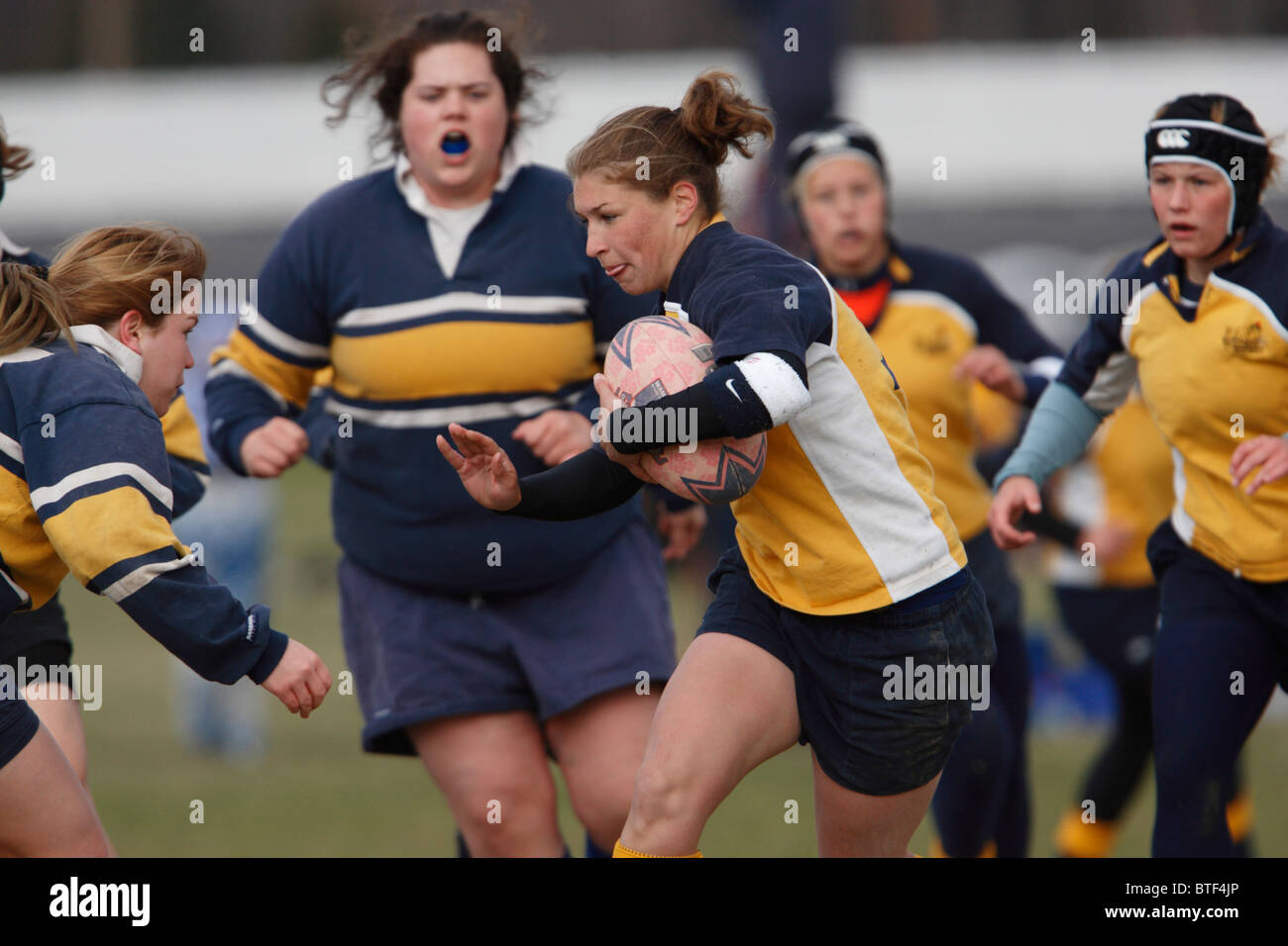 A Naval Academy player carries the ball during a women's rugby match against George Washington University. Stock Photo