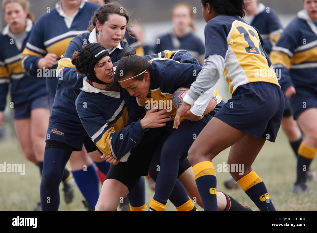 A Navy ball carrier is tackled by a Georgetown University opponent during a women's rugby match. Stock Photo
