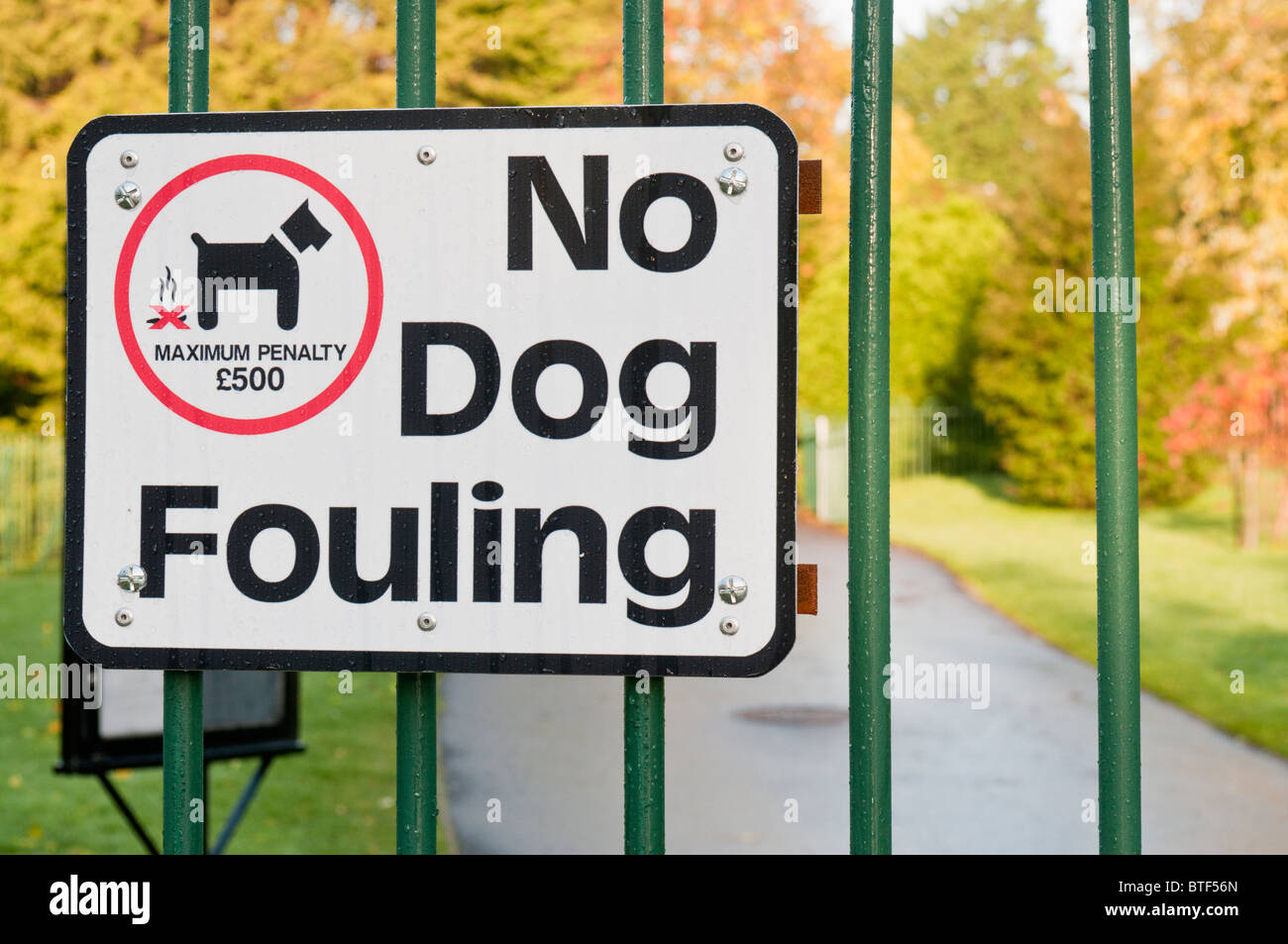 'No Dog Fouling' sign on a park gate warning owners they can be fined £500 for not picking up dog waste. Stock Photo