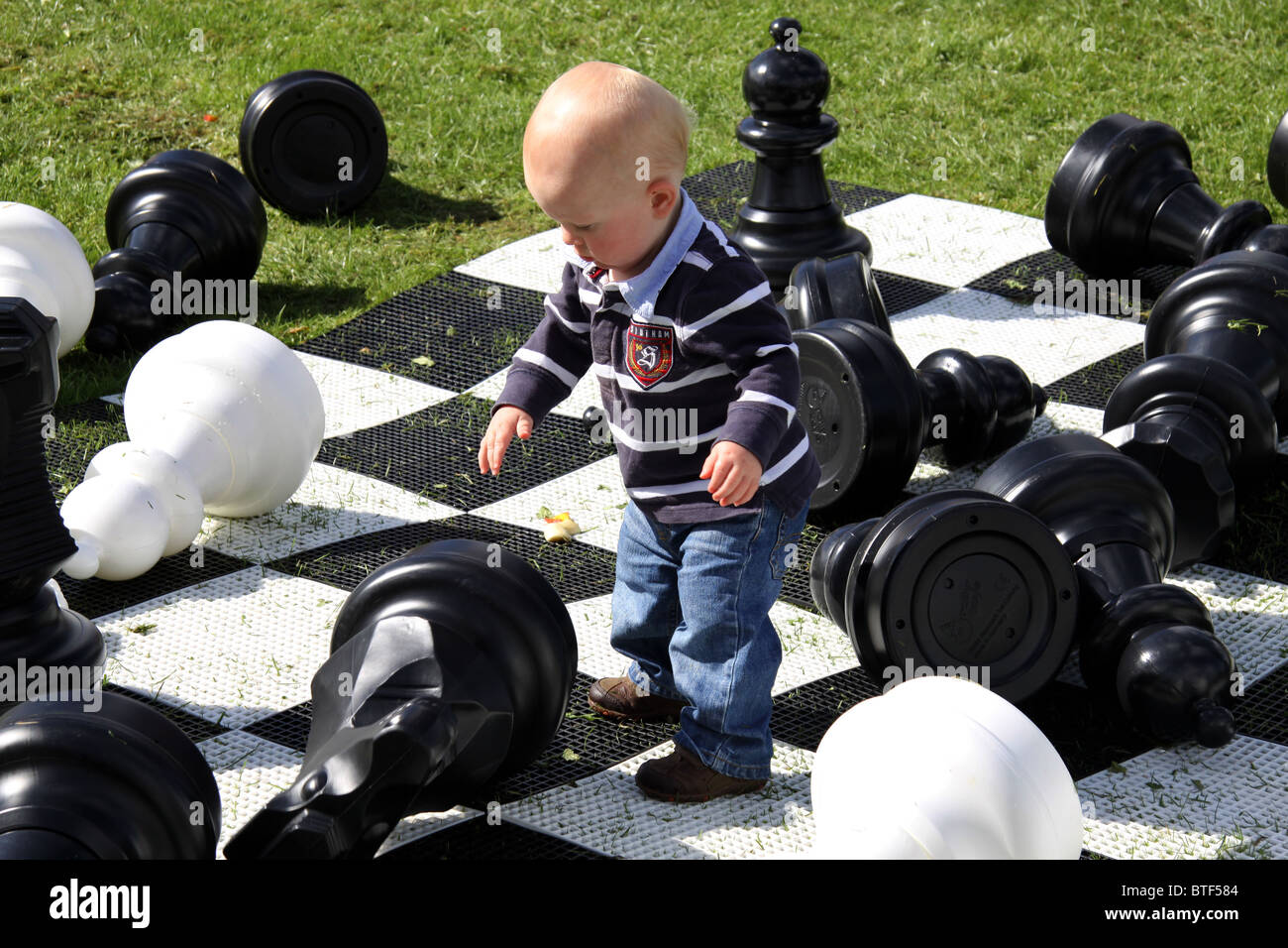 Young boy playing with large chess pieces outdoors in the UK Stock Photo