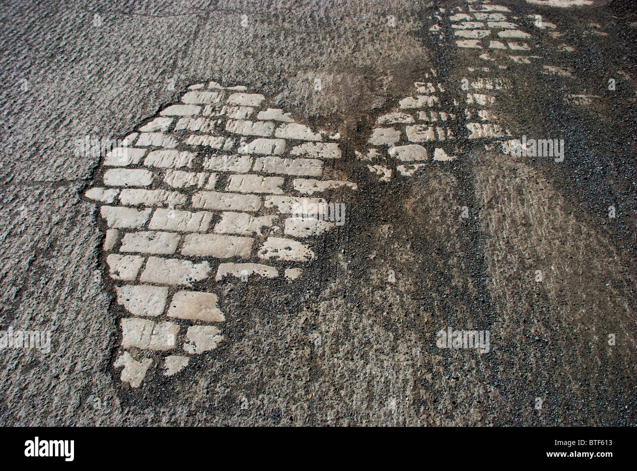 Exposed old stone foundation road beneath roughed macadam awaits resurfacing Stock Photo