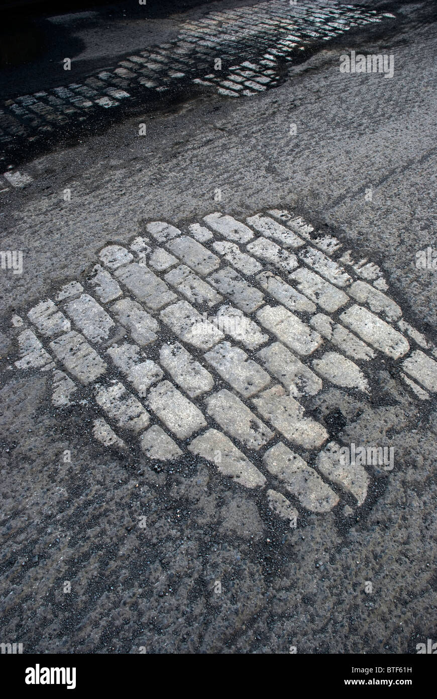 Exposed old stone foundation road beneath roughed macadam awaits resurfacing Stock Photo