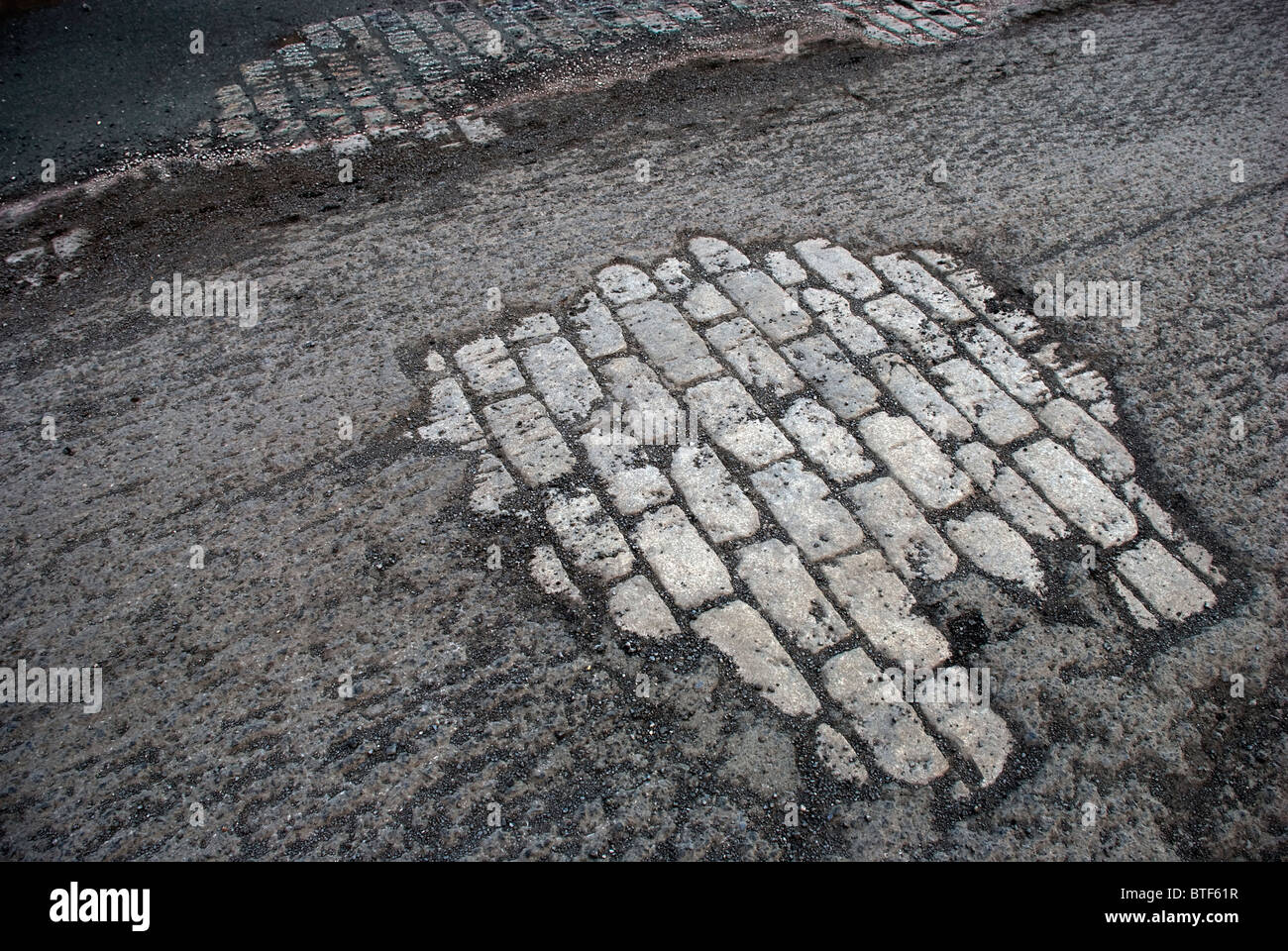 Exposed old stone foundation road beneath roughed macadam awaits resurfacing Stock Photo