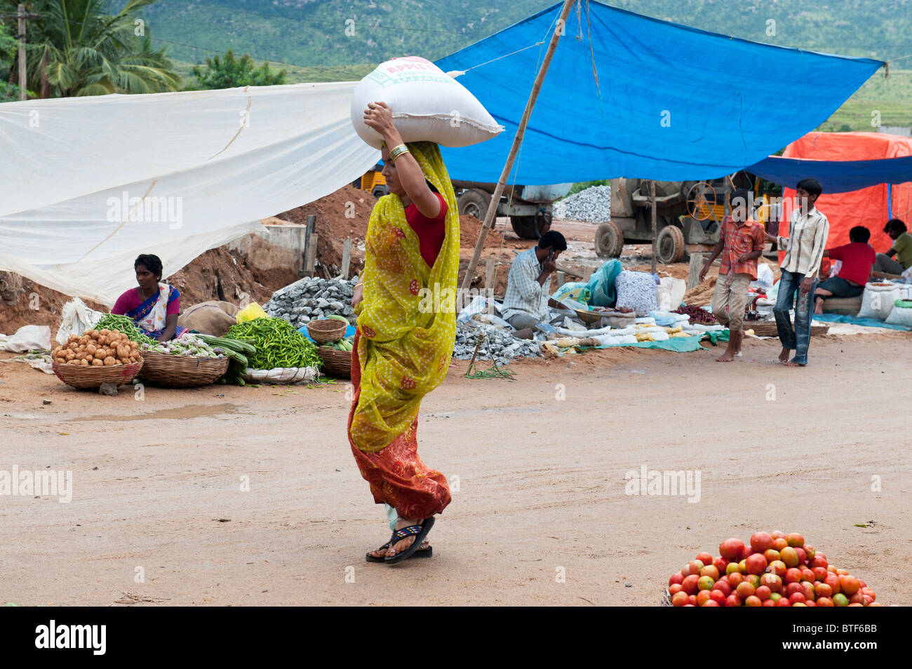 Indian woman carrying shopping on her head at market in Puttaparthi, Andhra Pradesh, India Stock Photo