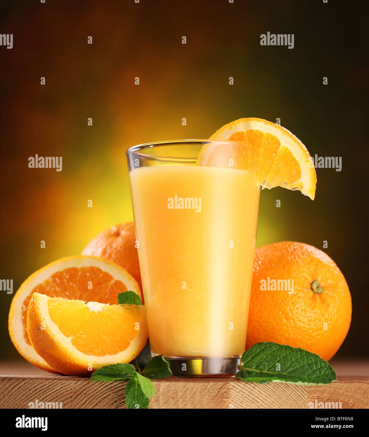Still life: oranges and glass of juice on a wooden table. Stock Photo