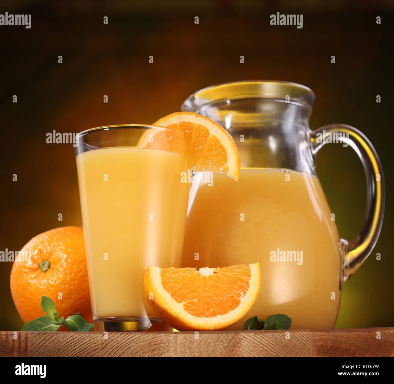 Still life oranges, glass of juice and jug full of juice on a wooden