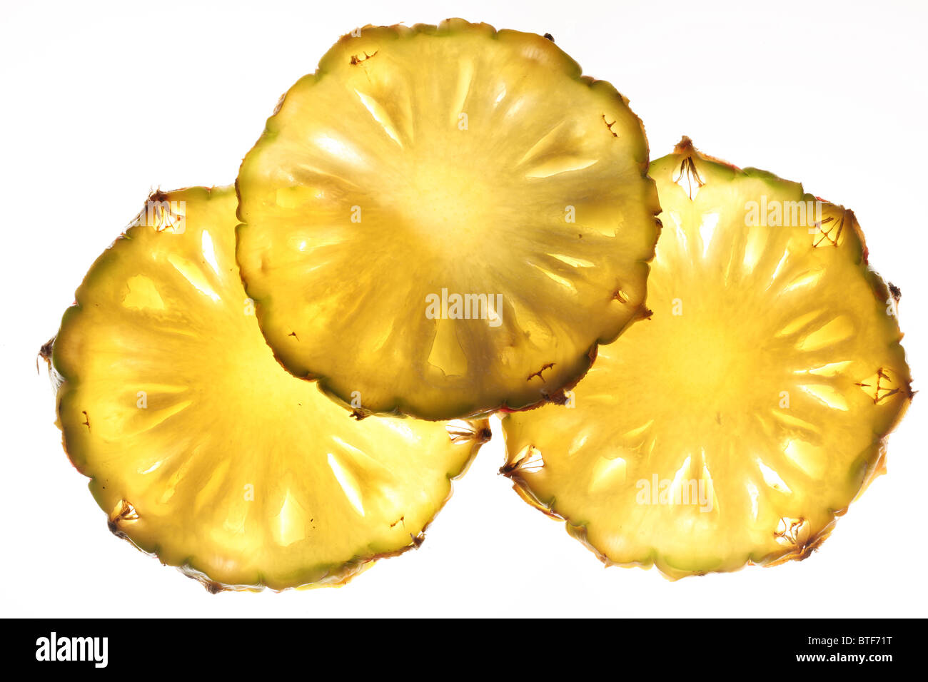 Cross cuts of pineapple back lighted. Isolated on a white. Stock Photo