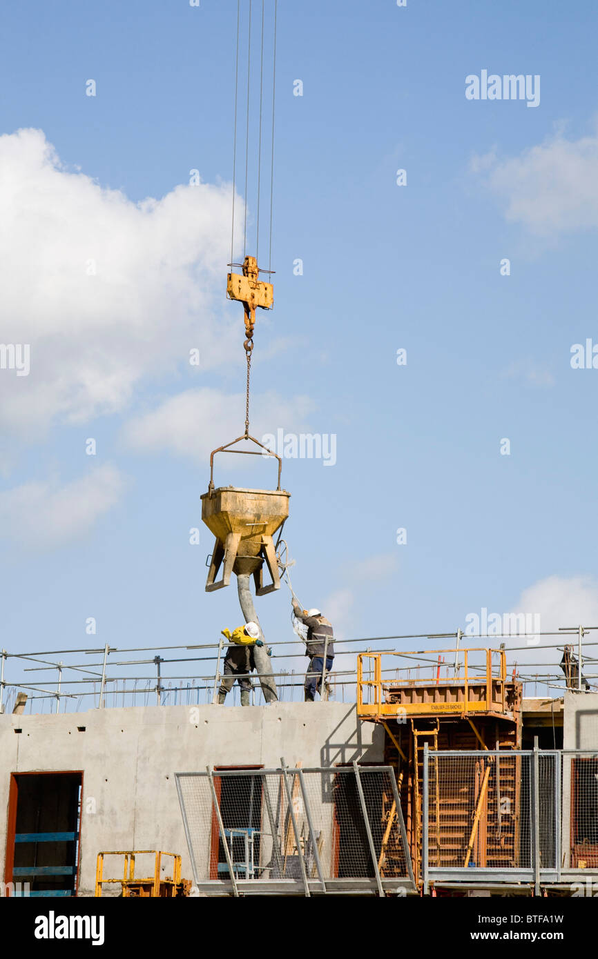 Construction workers guiding bucket suspended by crane to deposit ...