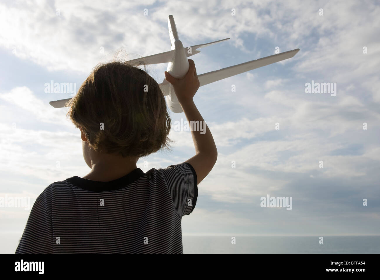 Boy playing with toy airplane, rear view Stock Photo