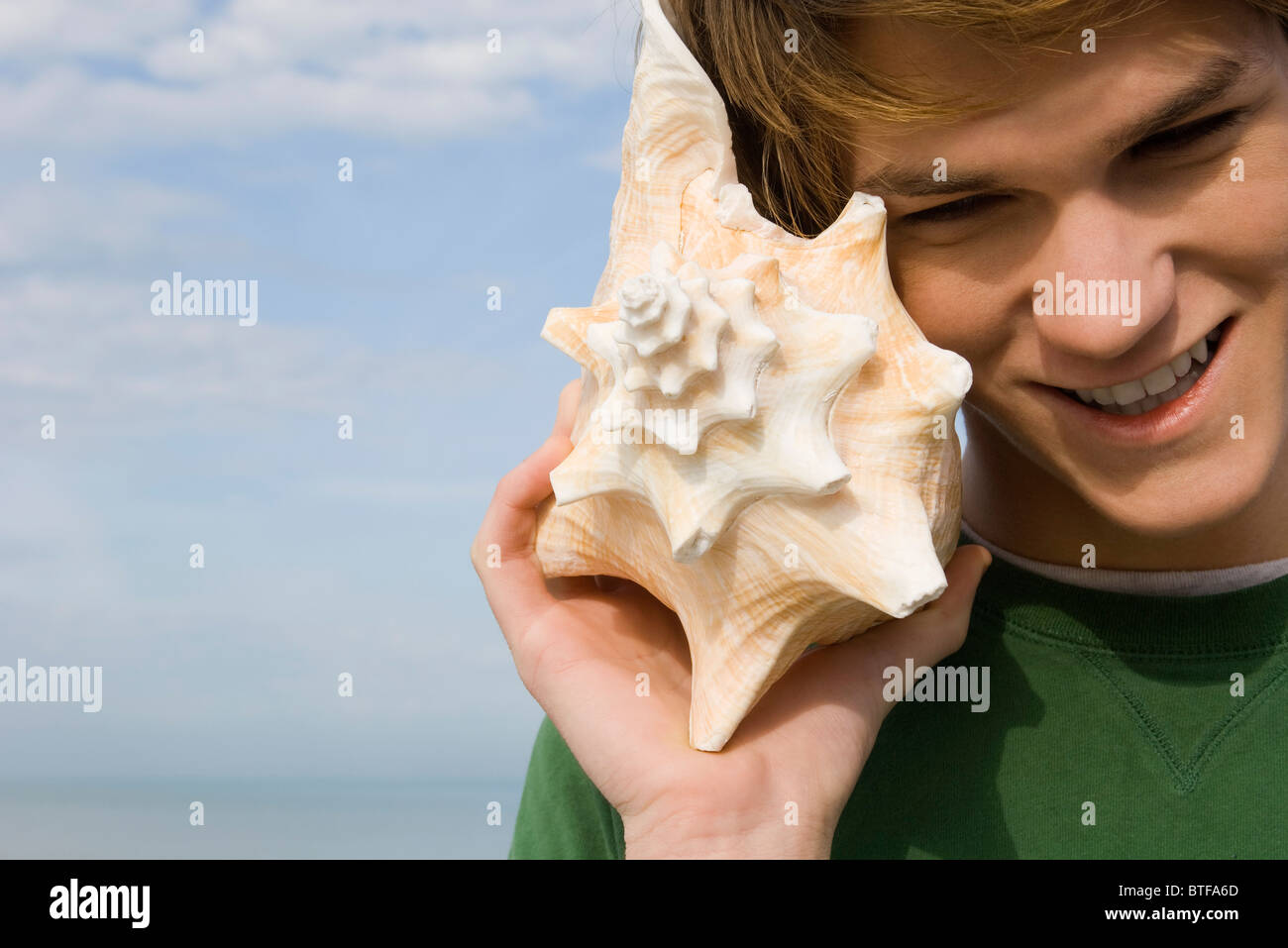 Young male listening to conch shell Stock Photo Alamy