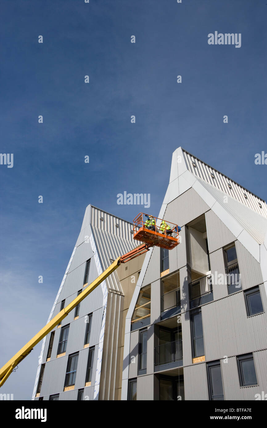 Construction workers in cherry picker bucket working on building ...