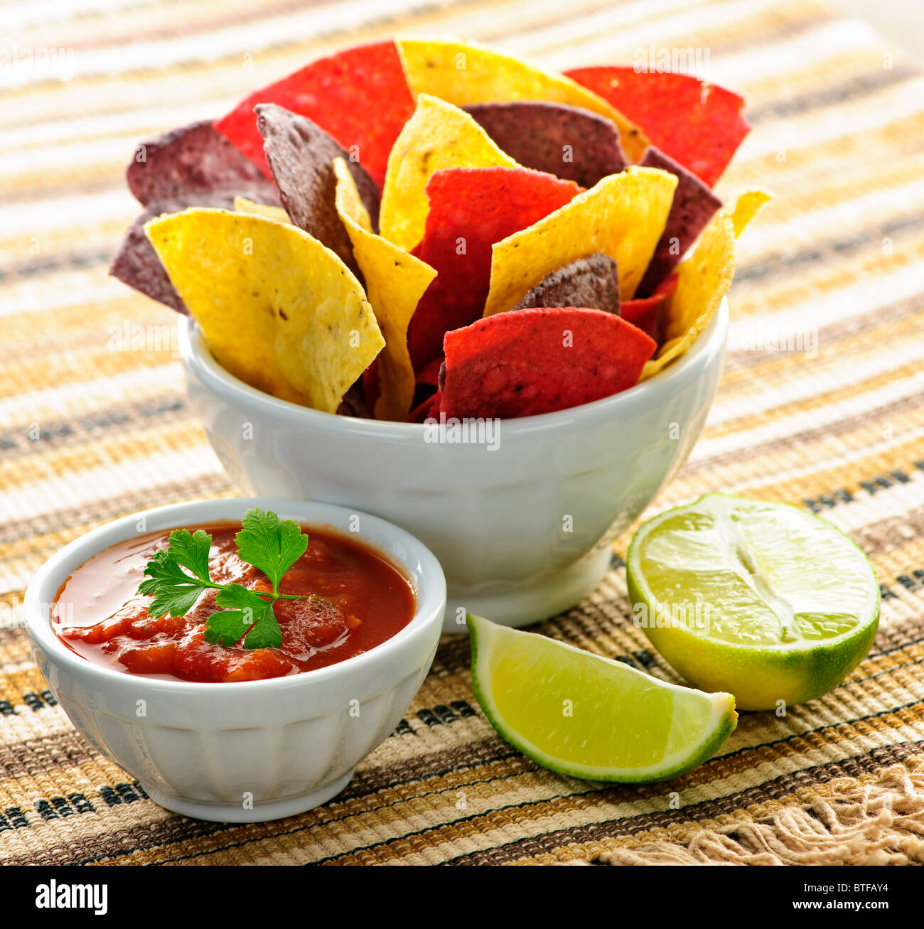 Bowl of salsa with colorful tortilla chips and lime Stock Photo