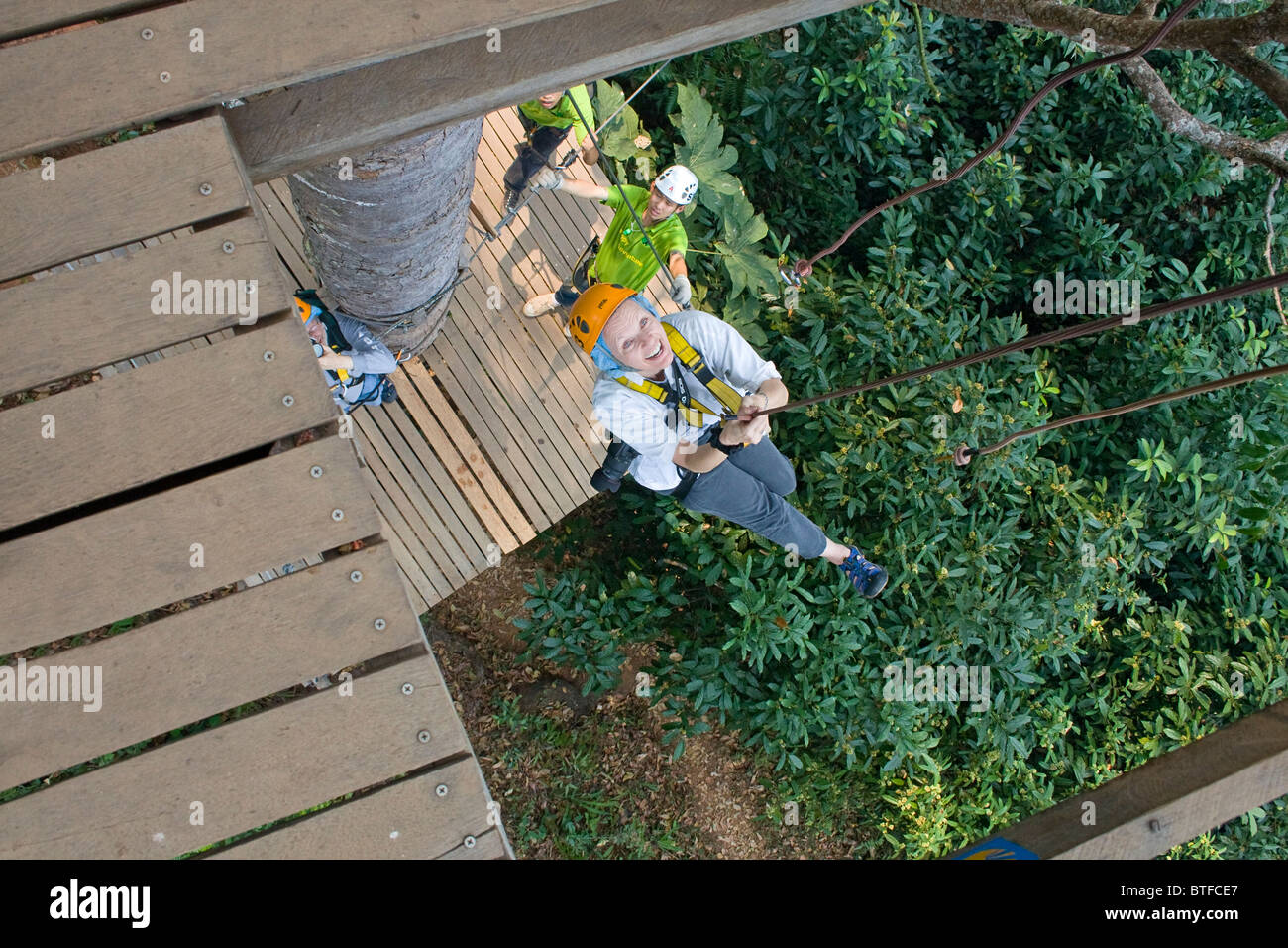 Woman is lowered on one of several 'drops' on ziplines at canopy tour in the Chiang Mai area of Thailand. Stock Photo