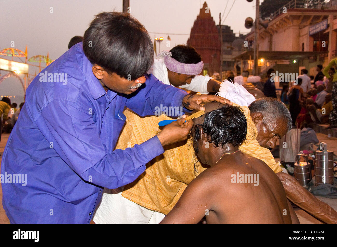 Man shaving the head of a worshiper, Varanasi, Uttar Pradesh, India Stock Photo