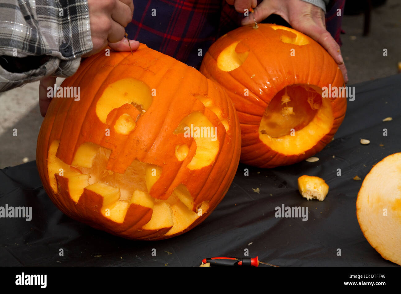 Two boys carve pumpkins into jack-o-lanterns during the Keene Halloween pumpkin festival in New Hampshire. Stock Photo