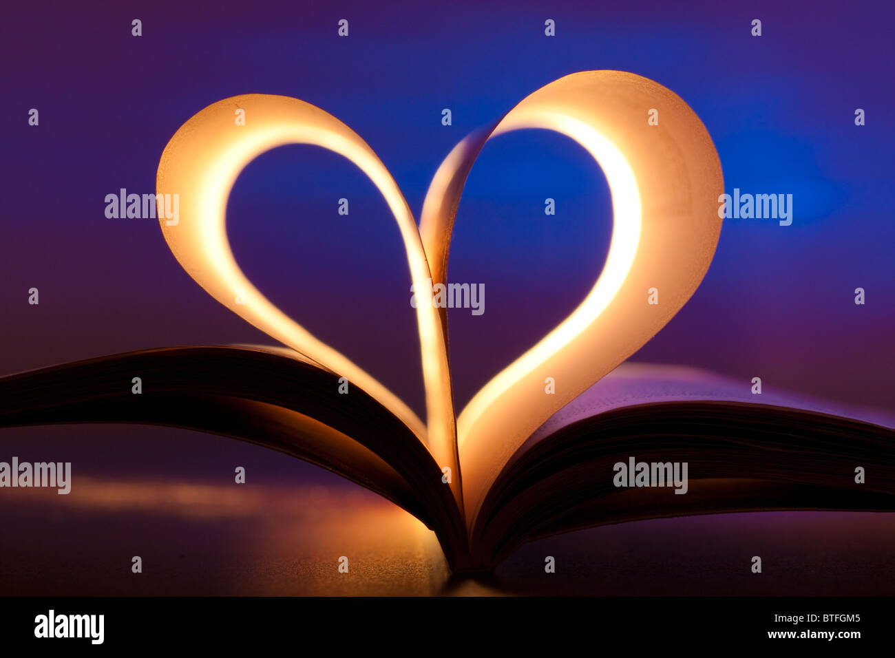 Open book in red heart shape on blue background Stock Photo