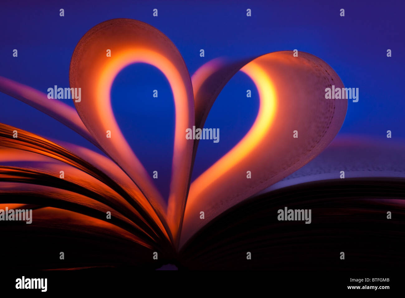 Open book in red heart shape on blue background Stock Photo