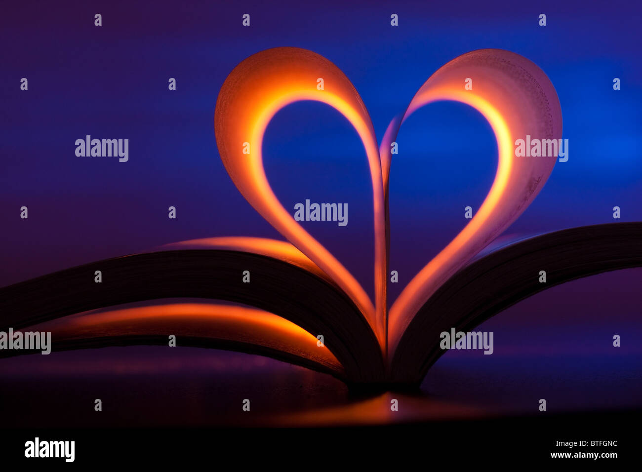 Open book in red heart shape on blue background Stock Photo