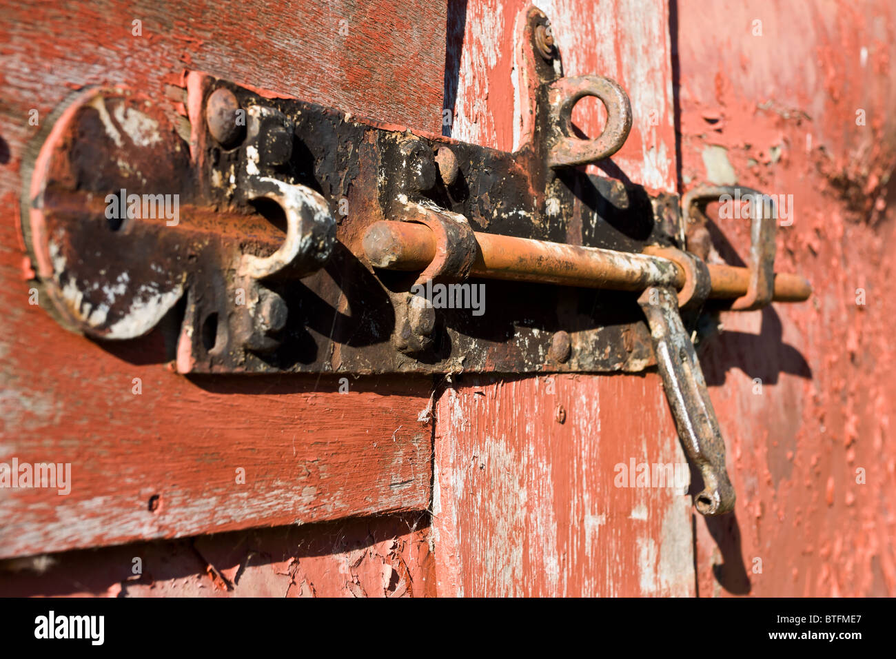 Close up of rusty old door bolt on barn door with peeling paint Stock
