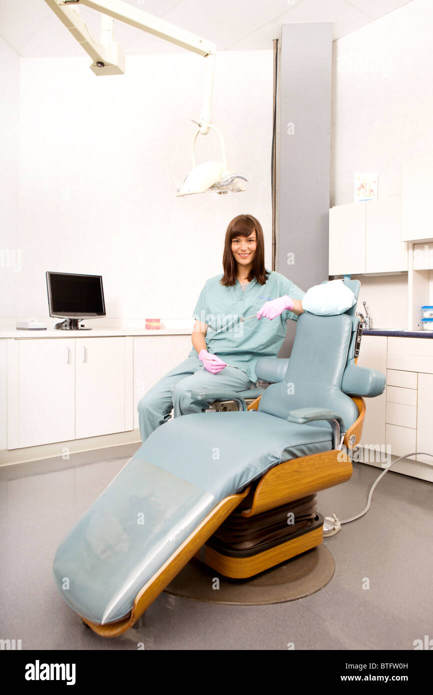 A dental hygienist sitting at a dental chair in a clinic Stock Photo