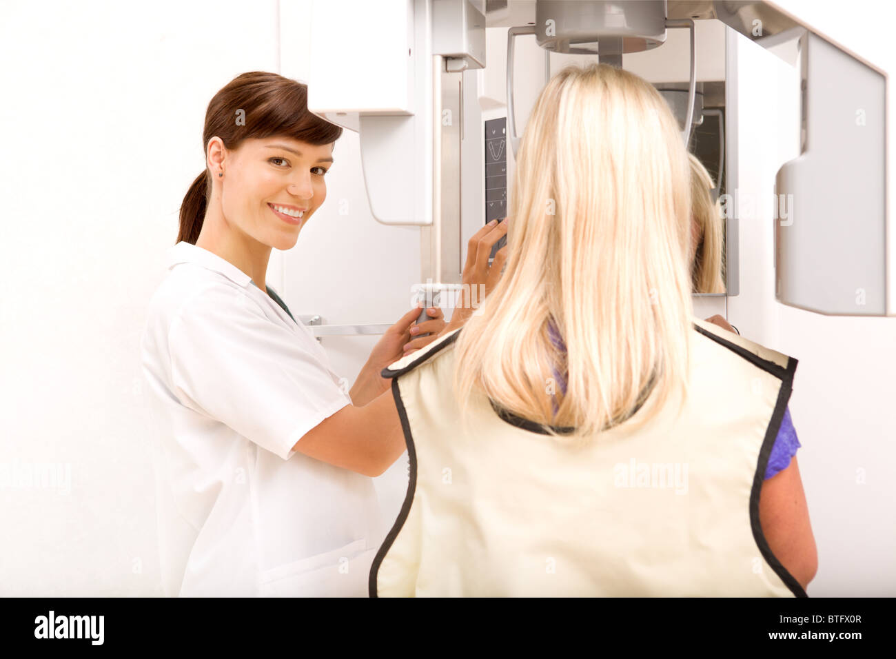 A woman taking a panoramic digital x-ray of a patients teeth Stock Photo