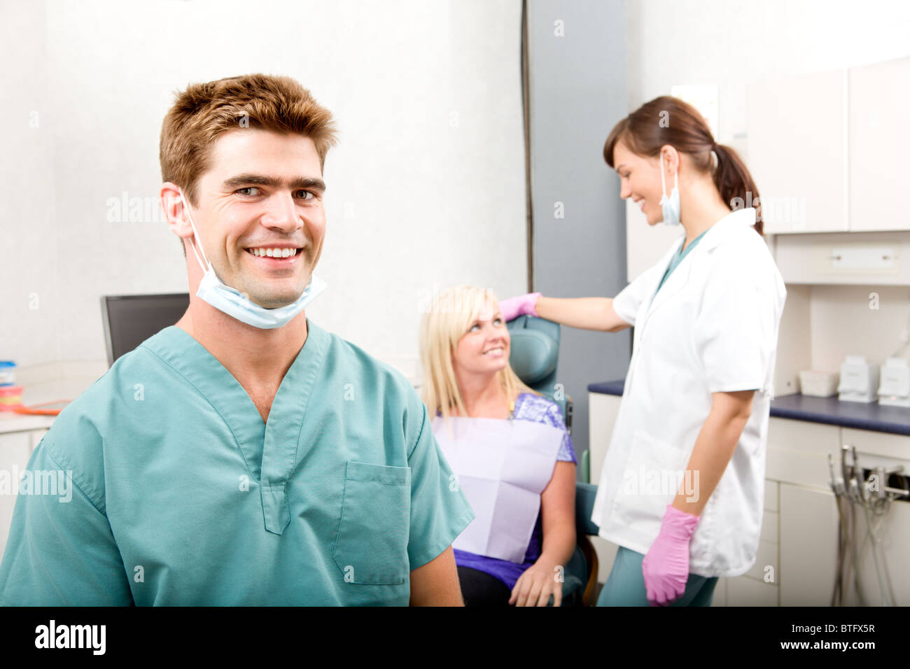 A happy smiling dentist at a clinic with an assistant and patient Stock Photo