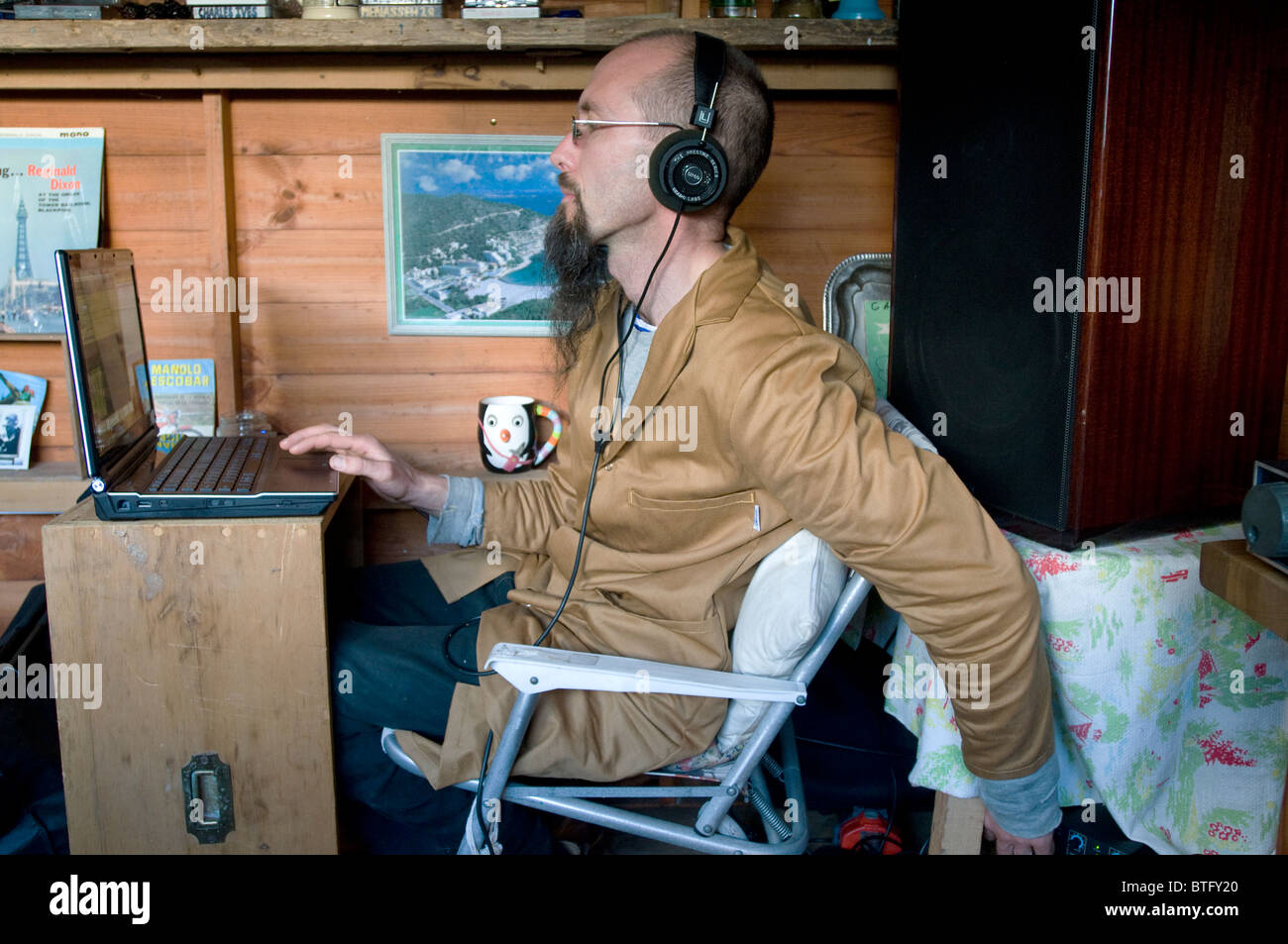 An eccentric 40 year-old man records music onto a computer in his shed Stock Photo