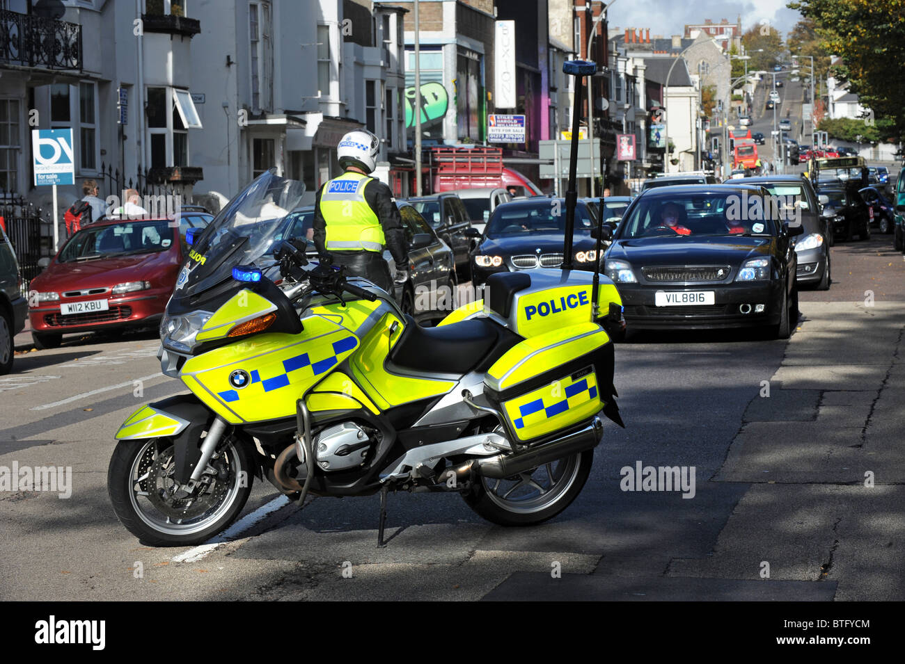 A police motorcyclist stops traffic before a march about cuts passes through the centre of Brighton Stock Photo