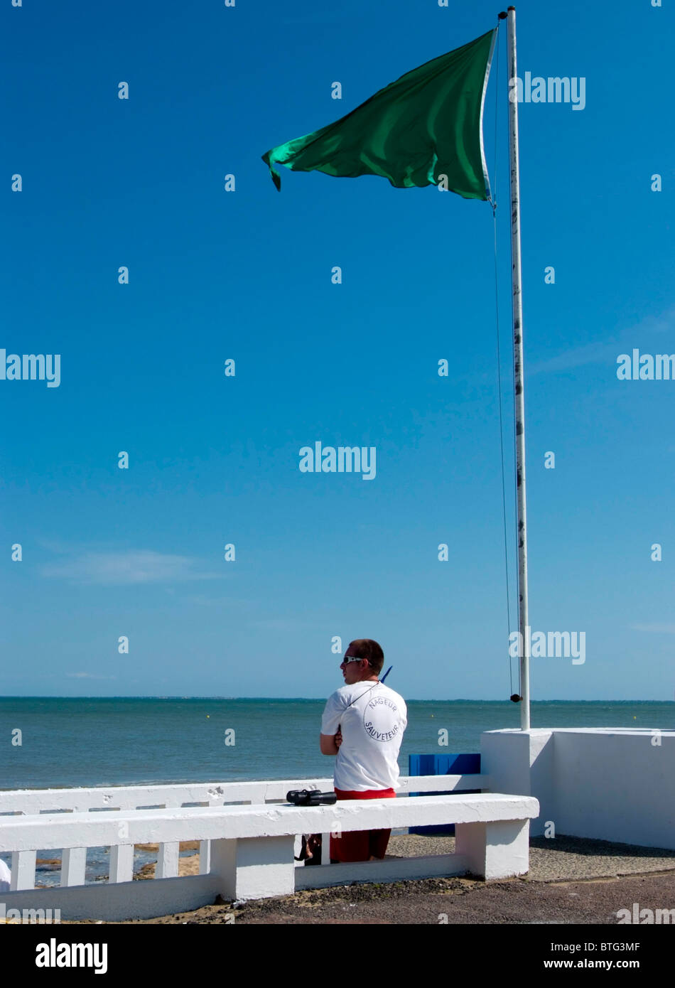French Life Guard on duty watching swimmers at the beach at La Tranche-Sur-Mer on a beautiful Summers day Stock Photo
